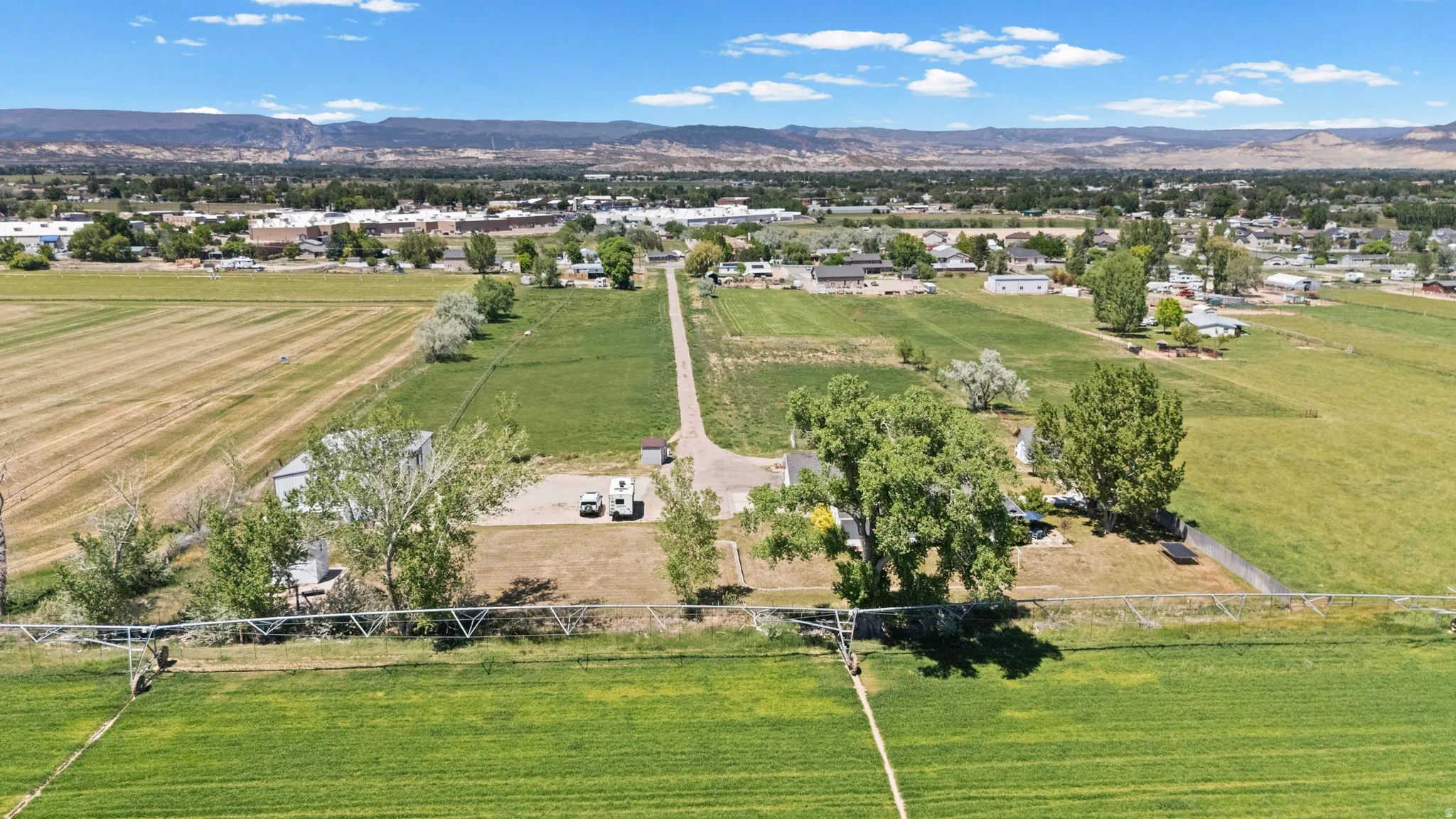 Extensive agricultural land featuring cultivated fields, a long private driveway, and mature trees