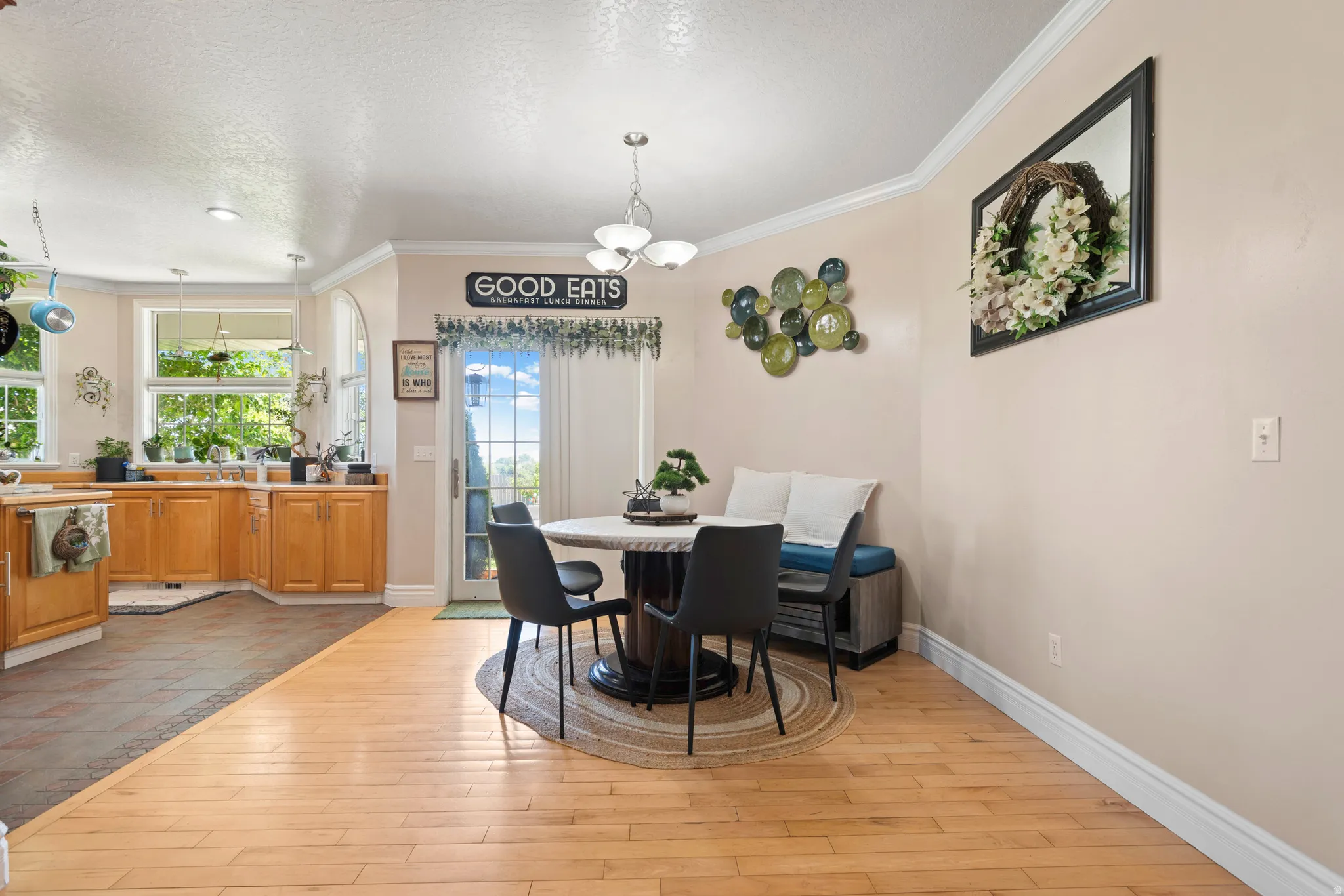 Bright dining area featuring wood-finish flooring and crown molding