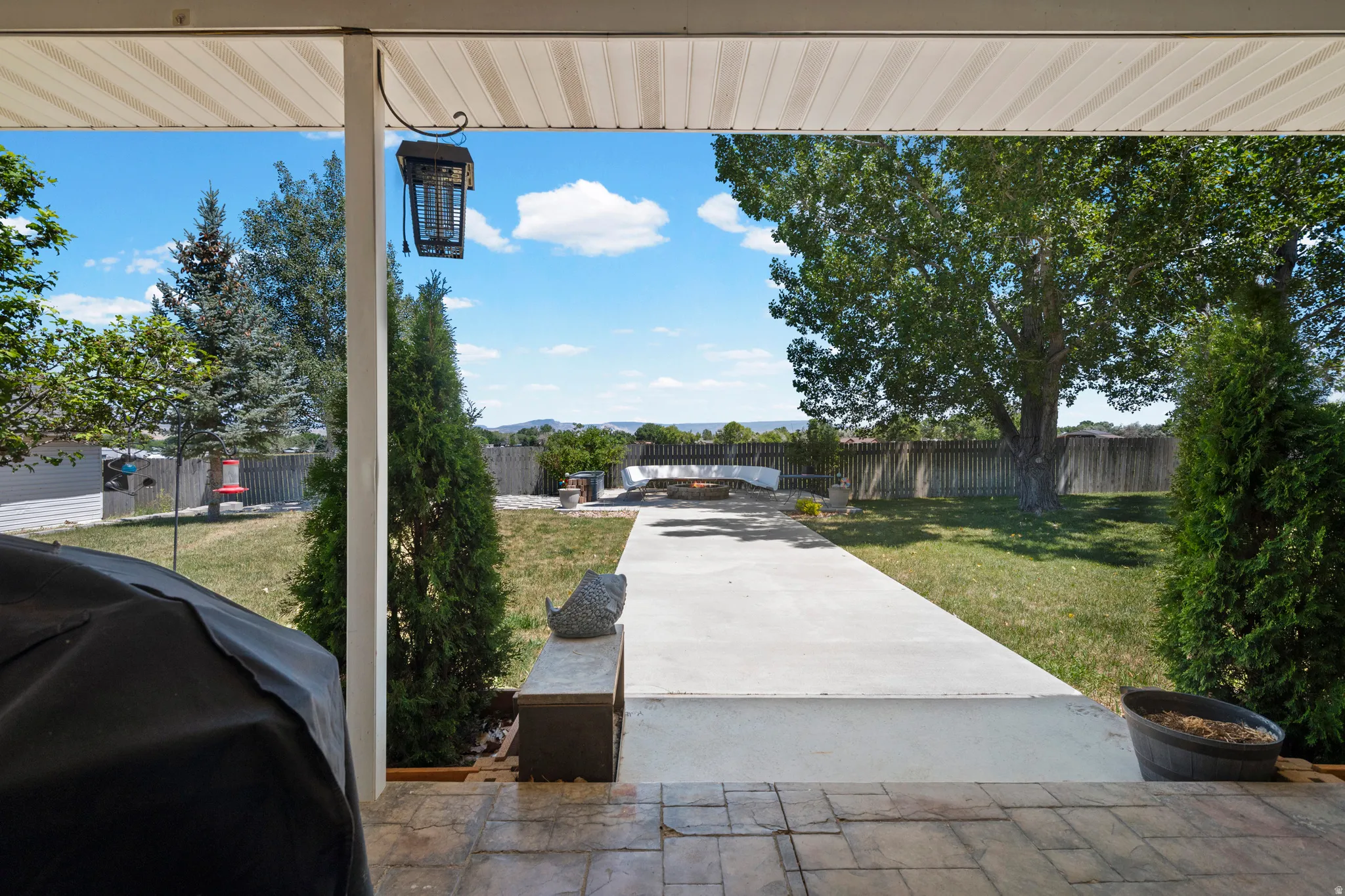 Covered patio with a patterned concrete surface opening to a spacious backyard