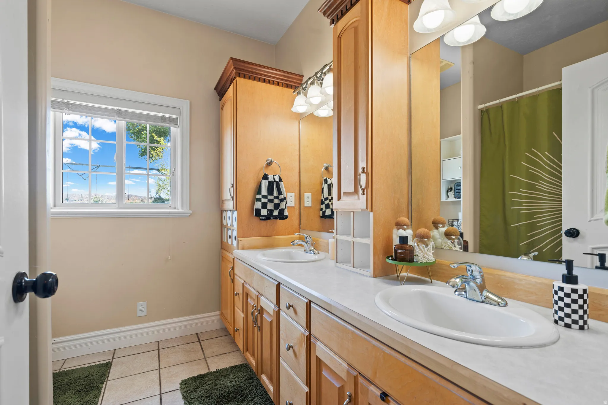 Dual vanity with light wood cabinetry, white countertops, and integrated sinks