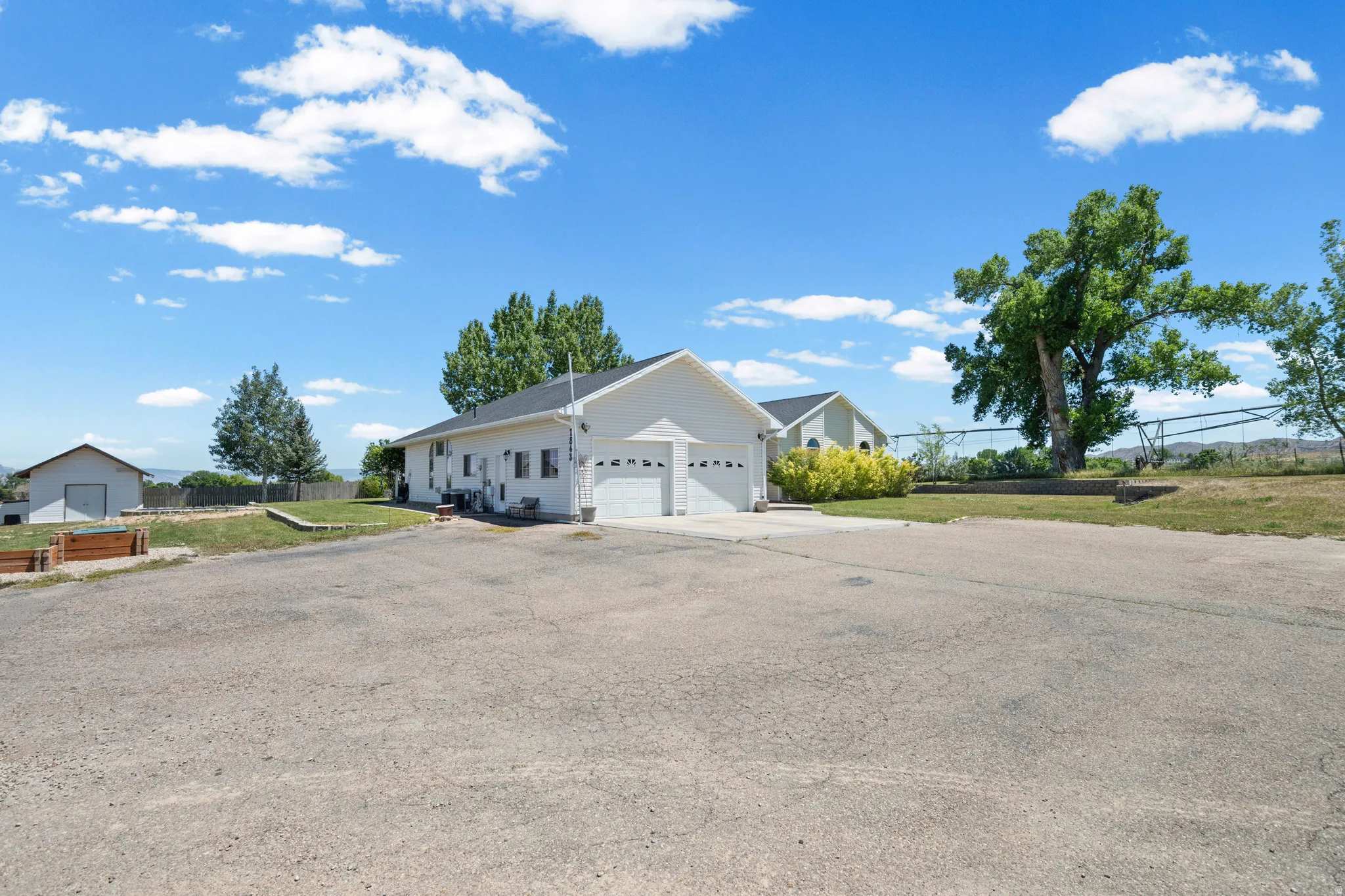 Expansive paved lot with a two-car garage and additional outbuilding