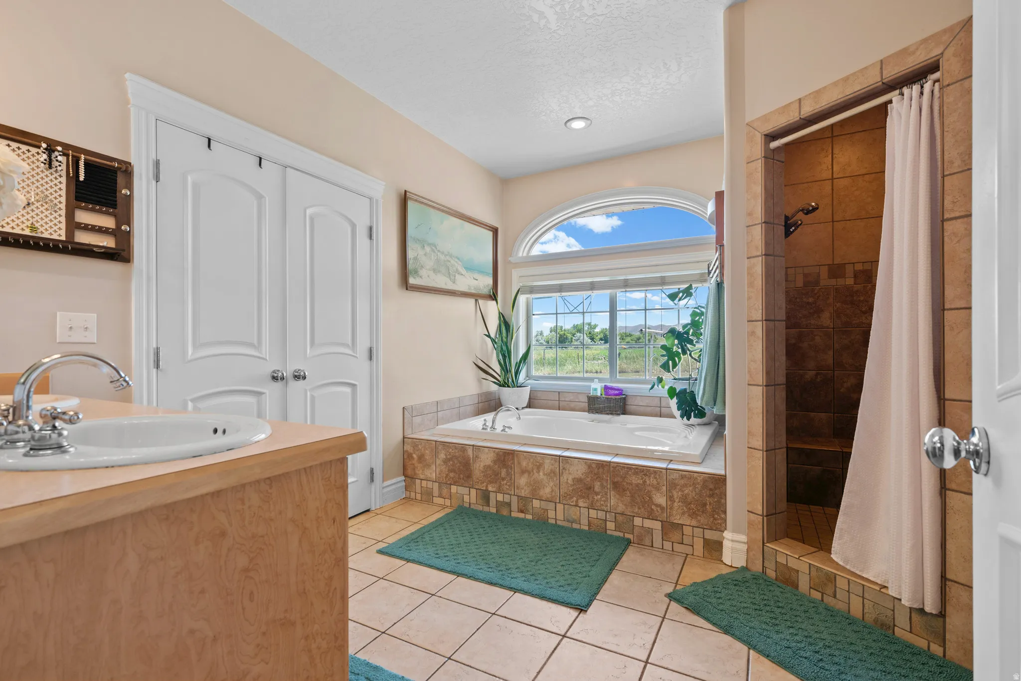 Bathroom featuring a built-in soaking tub with tiled surround, a separate tiled shower with a built-in bench, an arched window, and a single vanity with a laminate countertop