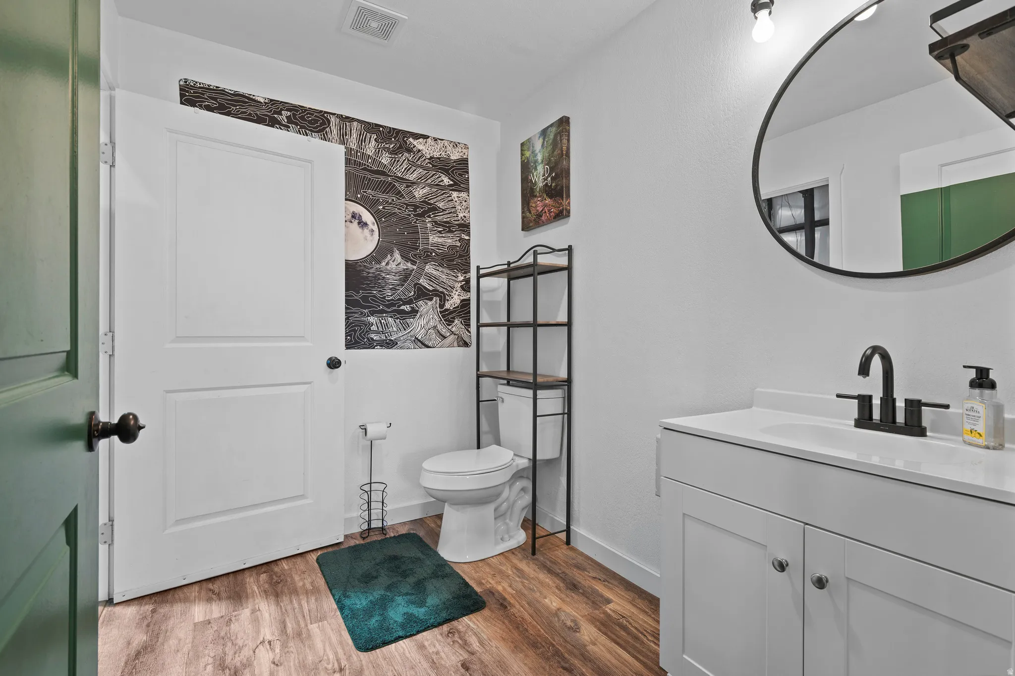 Bathroom featuring a white vanity with integrated sink, black matte faucet, and round framed mirror