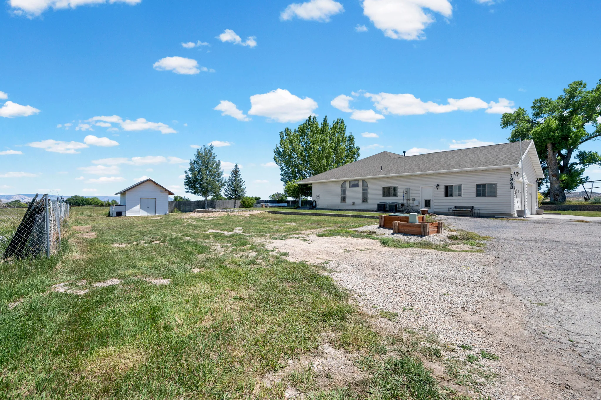 Ranch-style exterior with a gravel driveway, an attached two-car garage, and a separate storage shed