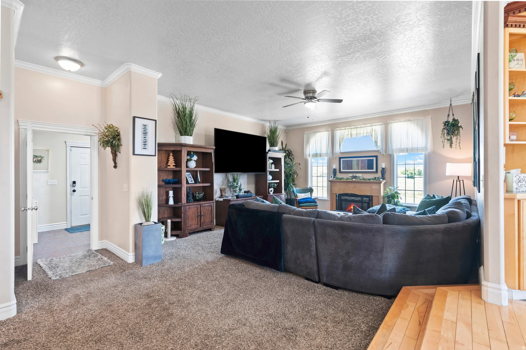 Spacious living area featuring carpet flooring, crown molding, a built-in fireplace, and large windows