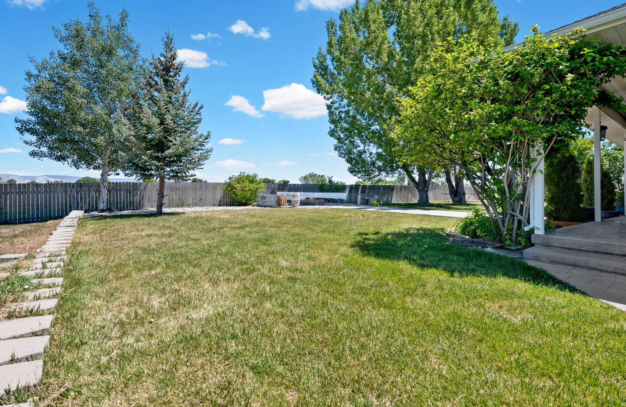 Expansive grassy yard with mature trees and a perimeter fence
