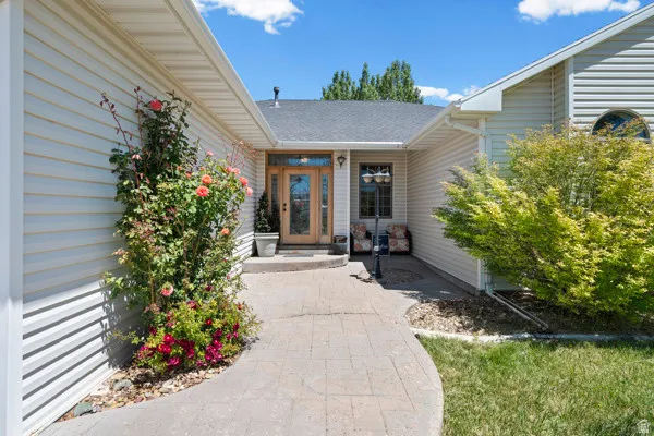 Stamped concrete pathway leading to a double-door entryway with sidelights, framed by a flowering rose bush and mature landscaping