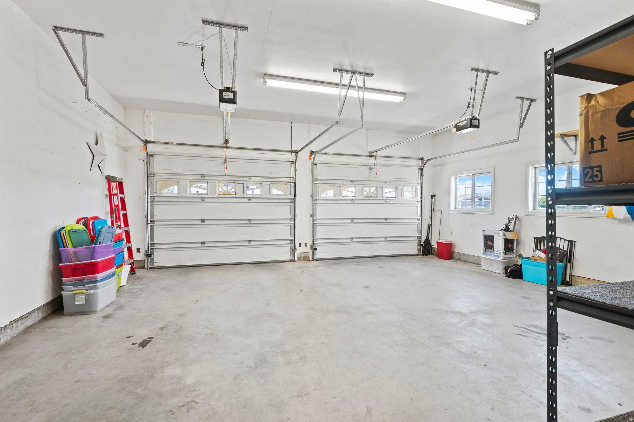 Two-car garage featuring automatic garage door openers, concrete flooring, and multiple windows