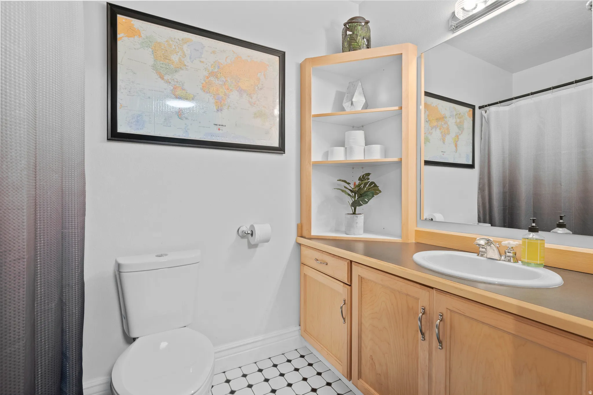 Bathroom featuring a light wood vanity, built-in shelving, and a black-and-white tiled floor