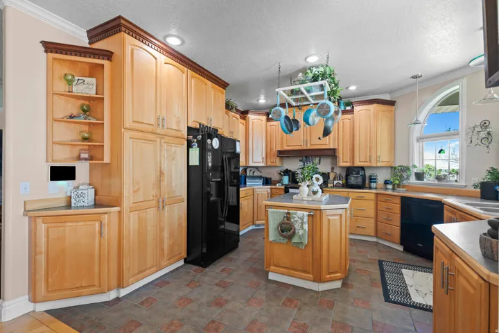 Kitchen featuring abundant light wood-finish cabinetry, a central island with countertop, and black appliances