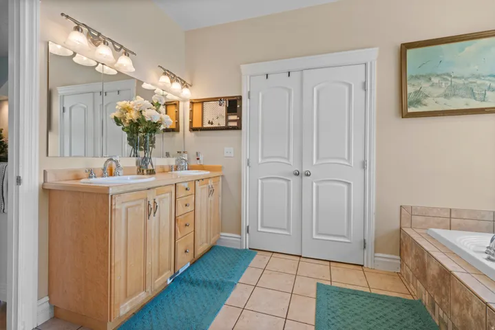 Dual vanity with light wood cabinetry, white sinks, and brushed nickel fixtures