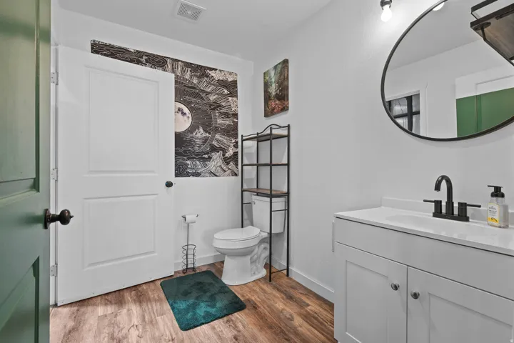 Bathroom featuring a white vanity with integrated sink, black matte faucet, and round framed mirror