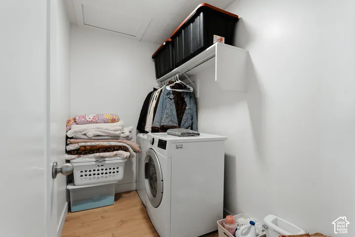 Laundry area featuring wood-finish flooring, white walls, and a built-in shelf with hanging rod