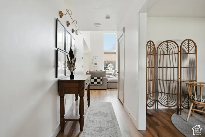 Spacious hallway with wood-finish flooring, white walls, and a decorative wall sconce fixture
