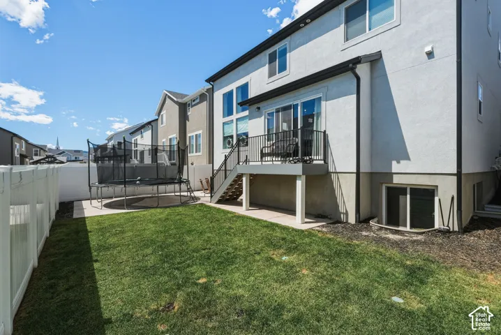 Private backyard featuring a manicured lawn, white vinyl fencing, and a concrete patio