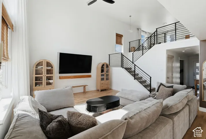 Two-story living area featuring high ceilings, wood-finish flooring, a contemporary staircase with black metal railings, and natural light from multiple windows