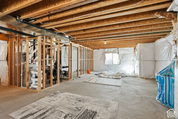 Unfinished basement featuring exposed wood joists, concrete flooring, and partial wall framing