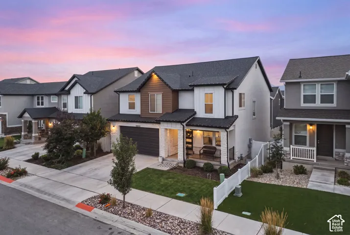 Contemporary two-story residence featuring white siding, brown wood-finish accents, and stone veneer detailing