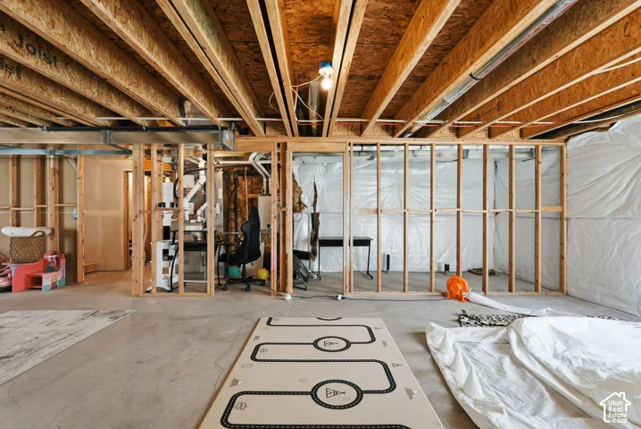 Unfinished basement offering expansive concrete flooring, exposed ceiling joists, and framed partition walls