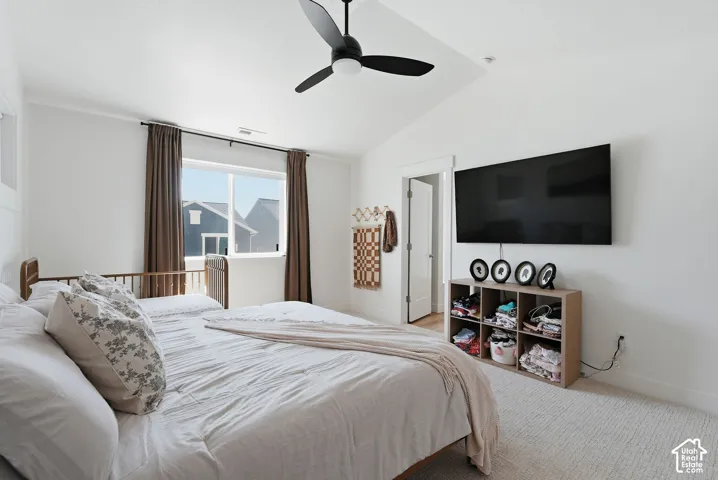 Vaulted ceiling featuring a black ceiling fan, white walls, and light-colored carpeting