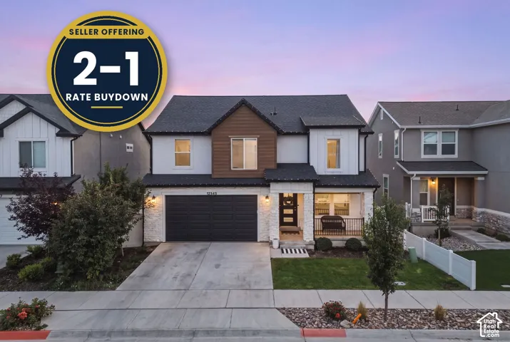 Two-story residence with a two-car garage, stone facade accents, covered entry porch, and black railing details