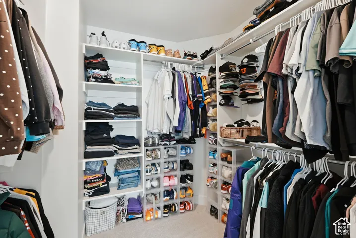 Walk-in closet featuring built-in shelving, multiple hanging rods, and integrated shoe storage