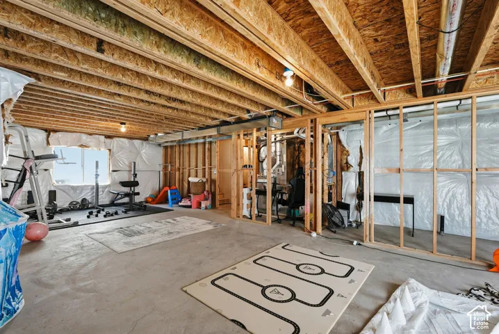 Unfinished basement featuring exposed wood framing, concrete flooring, and visible insulation