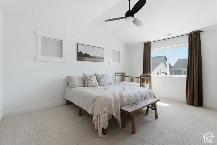 Spacious room featuring vaulted ceilings, a contemporary ceiling fan, and carpeted flooring