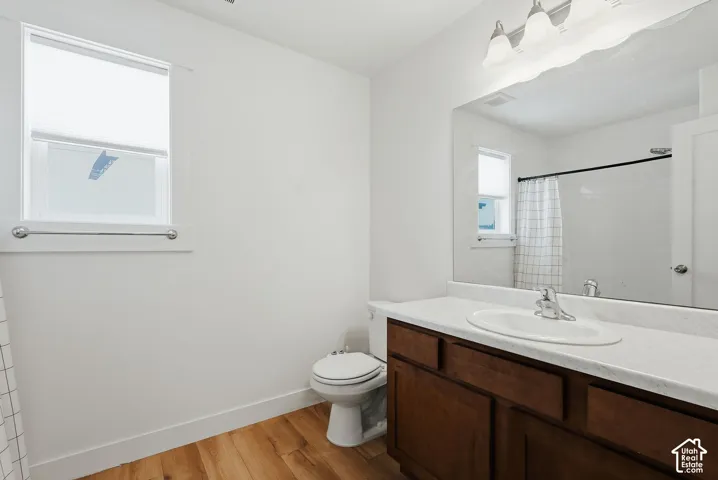 Bathroom featuring a wood-finish vanity with an integrated sink and counter, a large wall-mounted mirror, and a full-size window with privacy blinds