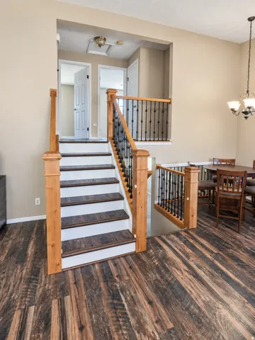 Hardwood-style flooring throughout, staircase with wood newel posts and balusters, wrought iron spindles, and a multi-tiered design