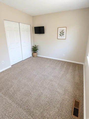 Warm neutral wall color, plush carpeted flooring, and white bi-fold closet doors