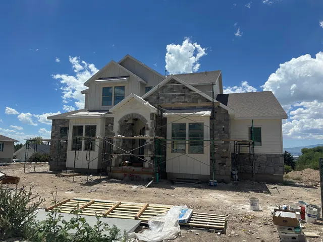 New construction residence featuring board and batten siding, stone veneer accents, and an arched entry