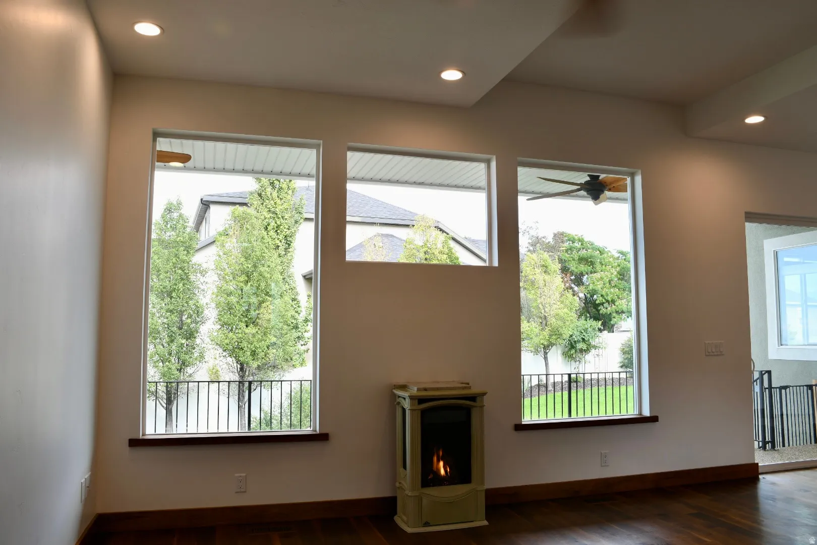Hardwood-finish flooring, recessed ceiling lighting, three expansive windows, tray ceiling, and a freestanding fireplace