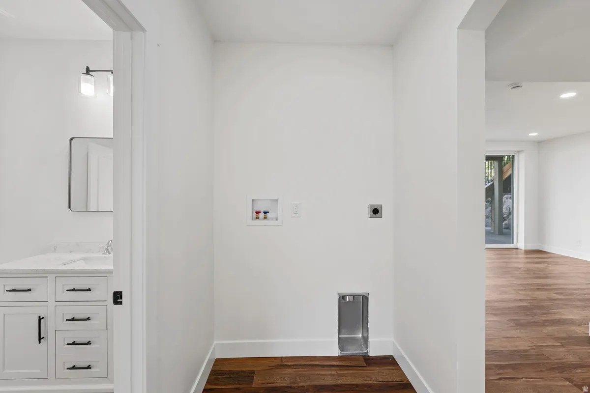 Dedicated laundry area with hookups, wood-finish flooring, and crisp white walls
