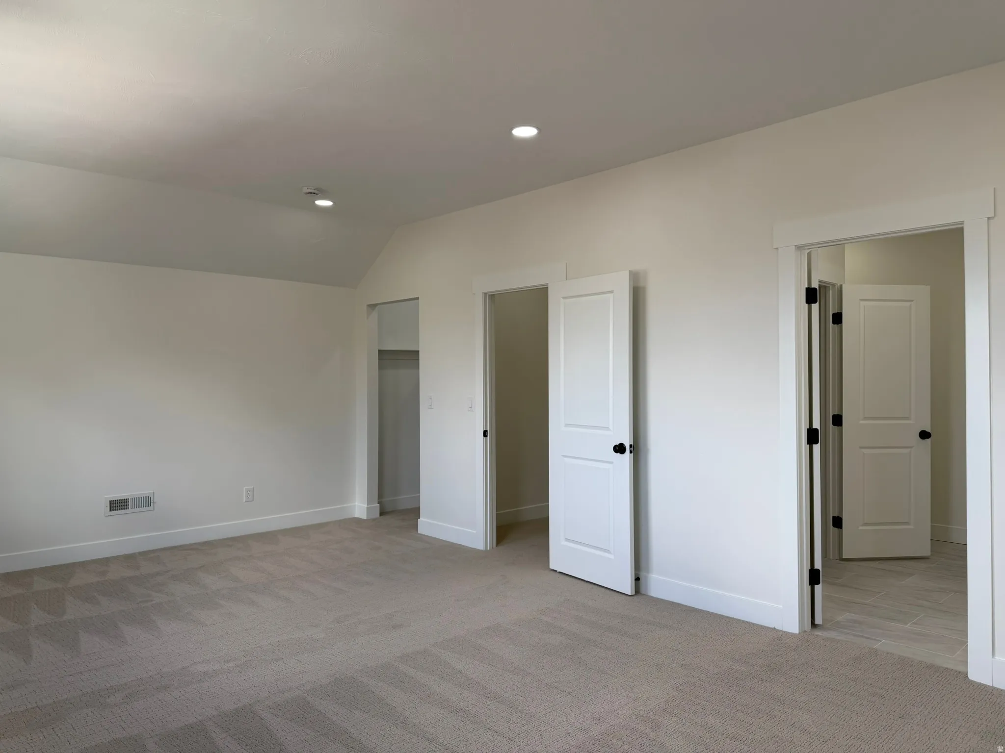 Soft carpeting, recessed ceiling lighting, crisp white trim, and solid panel doors