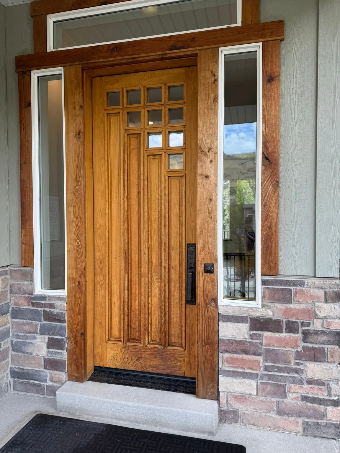 Craftsman-style wood entry door with multiple glass panes, framed by side lites and a transom window