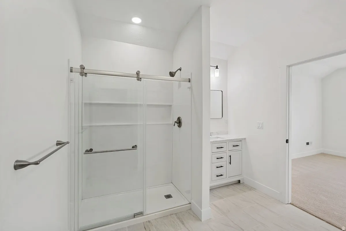 Shower with sliding glass doors, integrated shelving, and brushed nickel fixtures