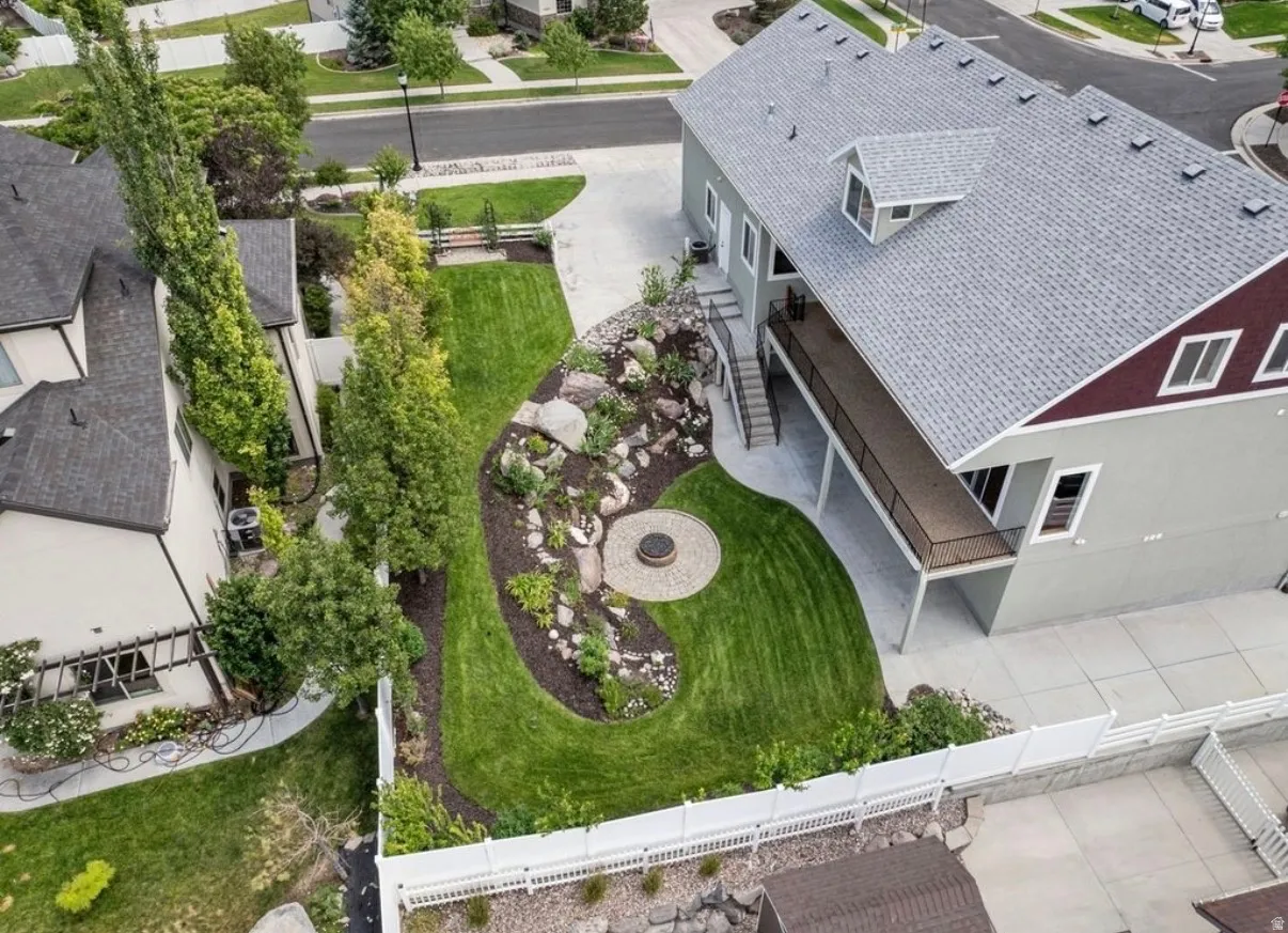 Expansive backyard featuring a manicured lawn, established landscaping, and a built-in fire pit