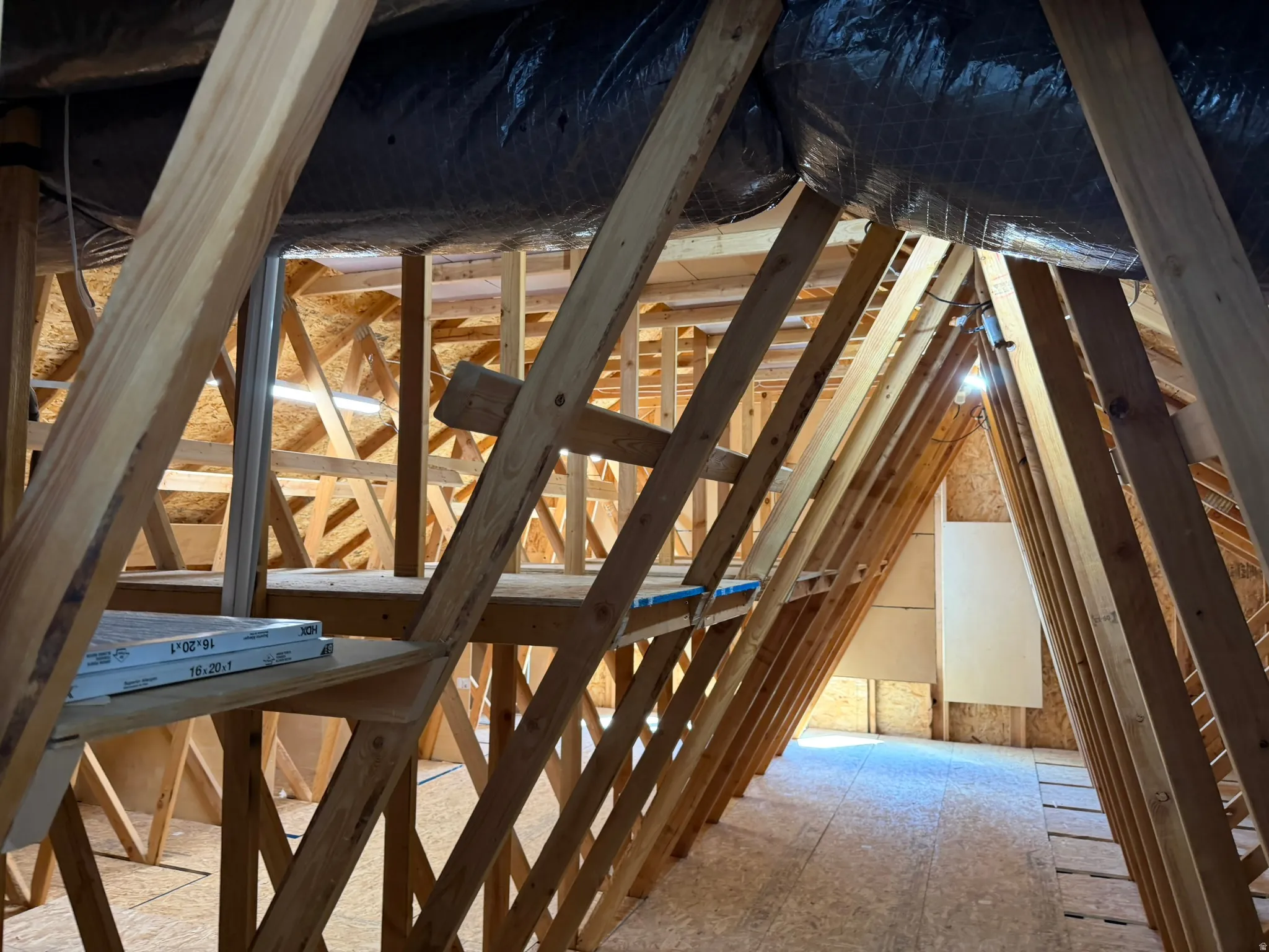 Unfinished attic space featuring exposed wood framing and a plywood floor