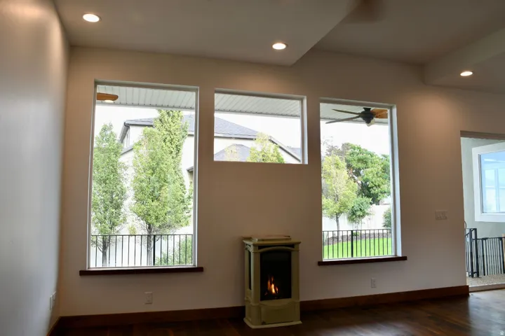 Hardwood-finish flooring, recessed ceiling lighting, three expansive windows, tray ceiling, and a freestanding fireplace