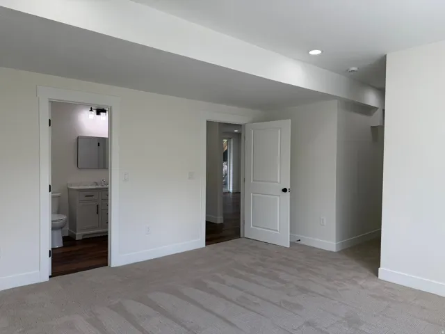 Recessed lighting, wood-finish flooring, white doors, and light neutral carpeting