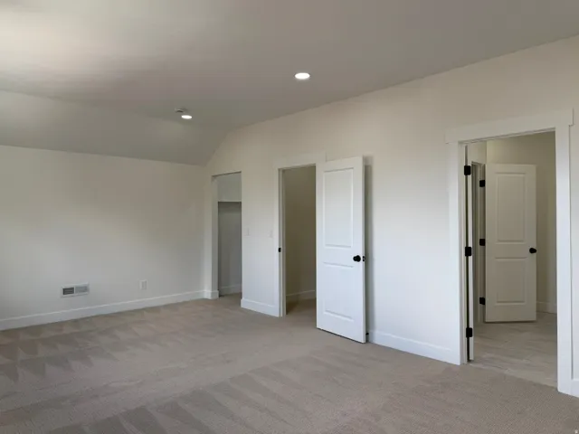 Soft carpeting, recessed ceiling lighting, crisp white trim, and solid panel doors