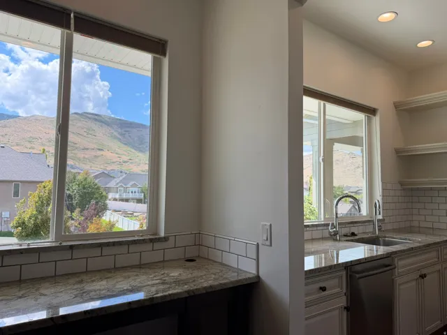 Kitchen area featuring granite countertops, a subway tile backsplash, white cabinetry, a stainless steel sink with a gooseneck faucet, and recessed lighting