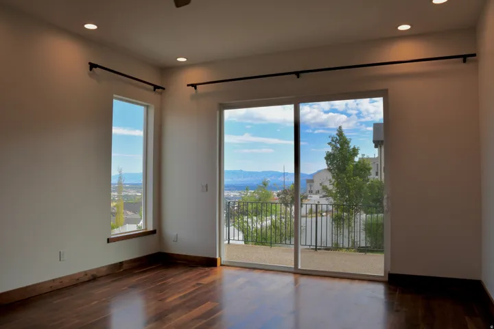 Wood-finish flooring, recessed lighting, and a full-light sliding glass door opening to an outdoor patio with metal railings