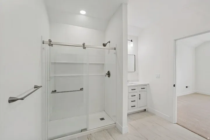 Shower with sliding glass doors, integrated shelving, and brushed nickel fixtures