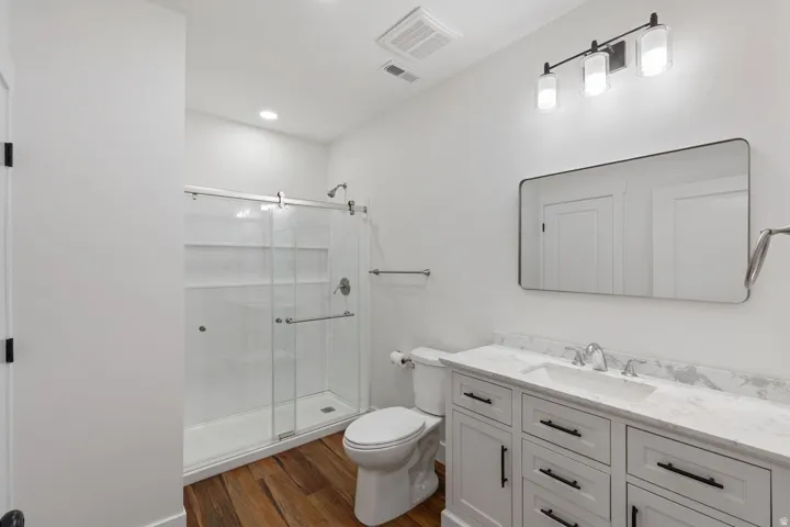 Bathroom featuring a white vanity with a stone-finish countertop, undermount sink, and black hardware