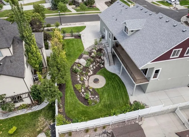 Expansive backyard featuring a manicured lawn, established landscaping, and a built-in fire pit