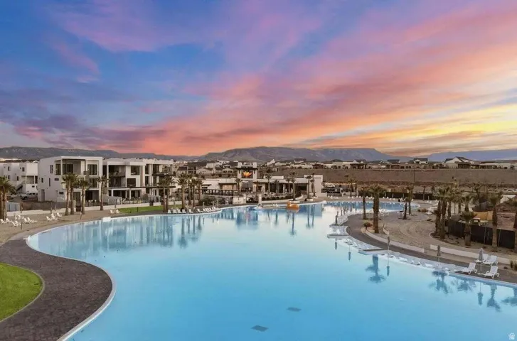 Expansive lagoon-style pool with surrounding sandy beaches and paved walkways