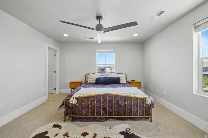 Bright bedroom with light neutral wall tones, recessed lighting, and a modern ceiling fan