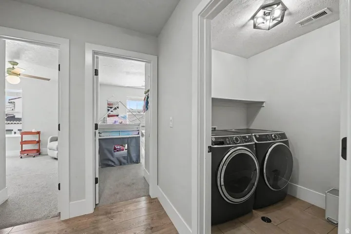 Dedicated laundry area featuring modern front-load washer and dryer units, a built-in shelf, and tile flooring